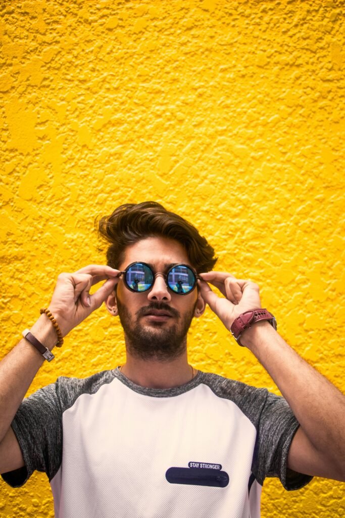pexels-photo-1192609-1192609 Young man with sunglasses standing against a vibrant yellow wall in daylight.