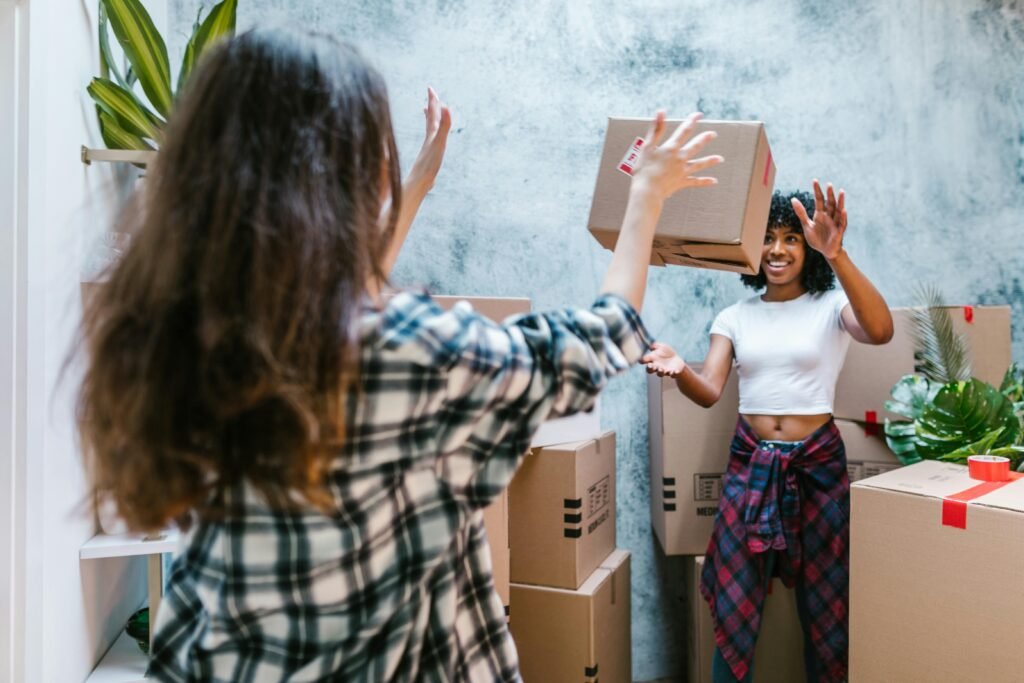 pexels-photo-7464476-7464476 Two women joyfully unpacking boxes in their new home, showcasing friendship and a fresh start.