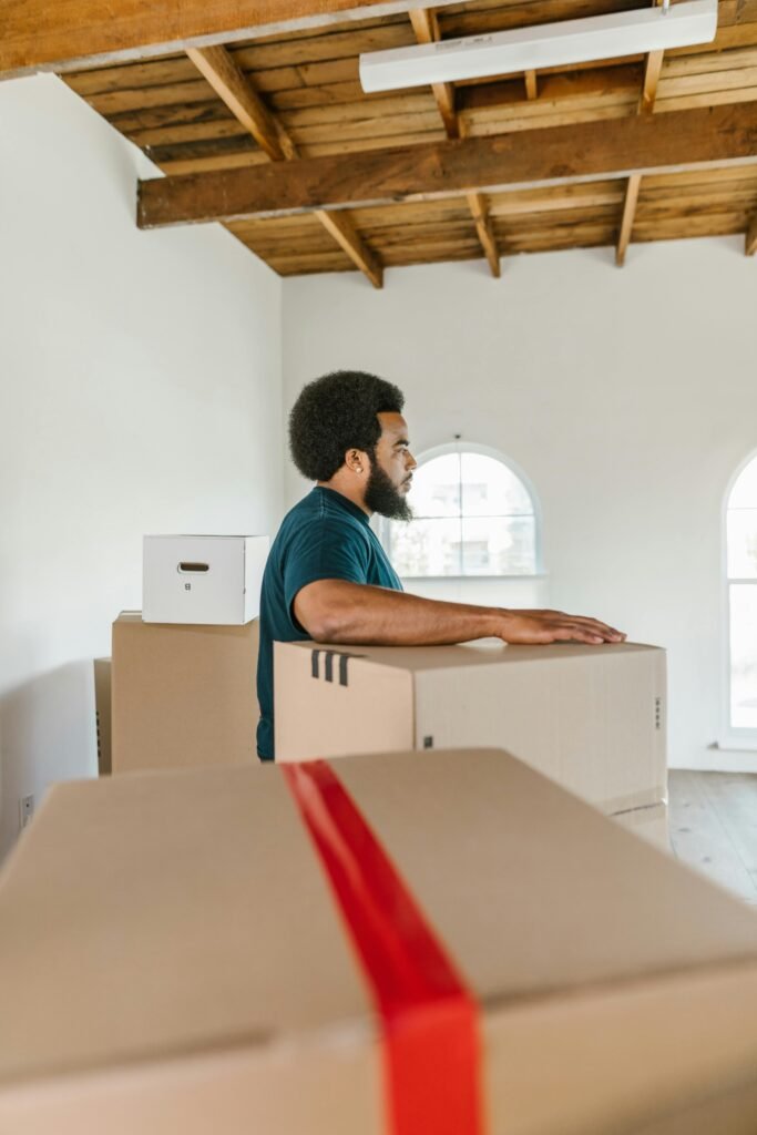 pexels-photo-7464686-7464686 Man handling moving boxes in a spacious, modern room during relocation.